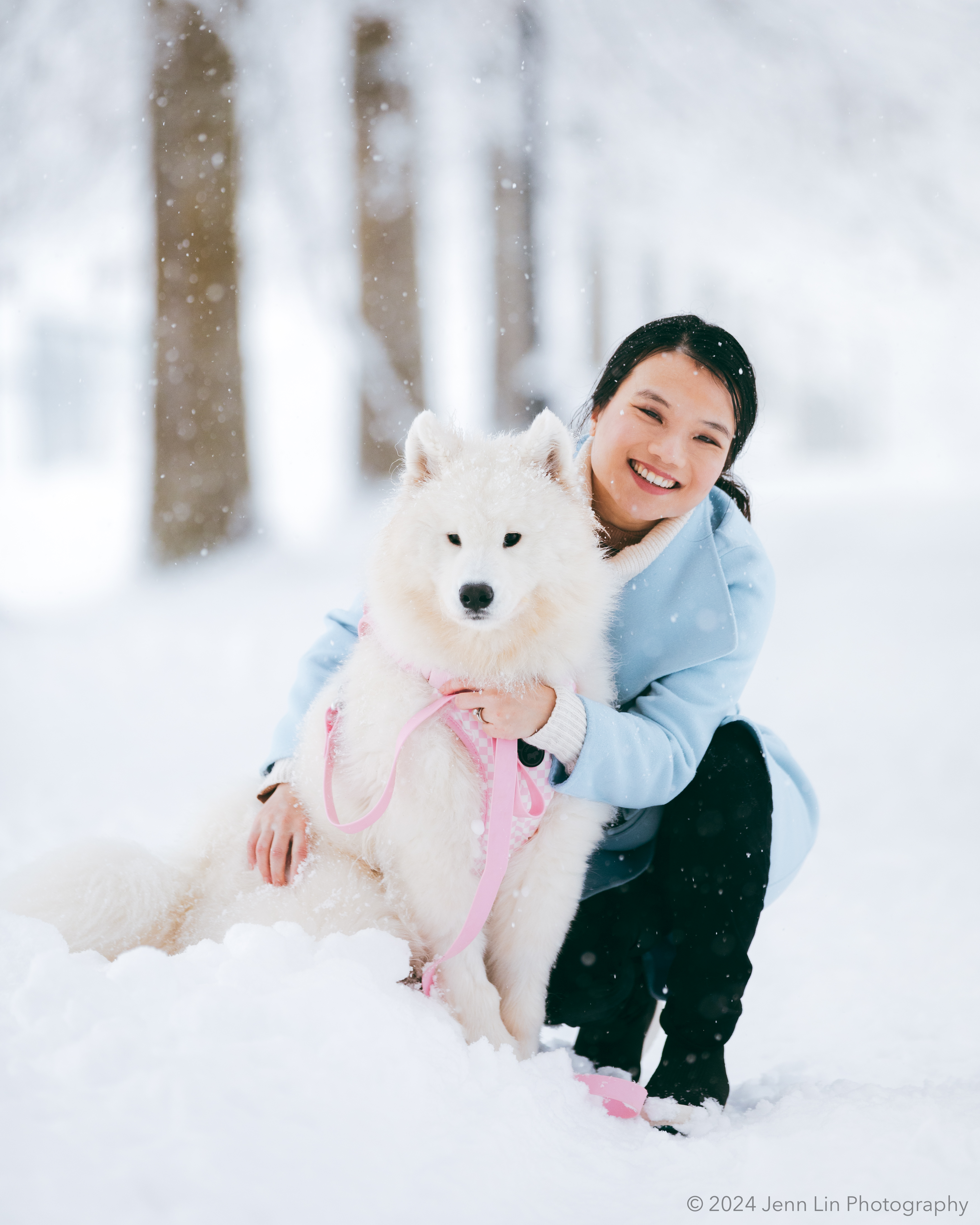Lily crouches to smile and hug her Samoyed puppy, Bao Bao, at King George Park in Richmond, BC. Photo captured for the story project, Dogs Will Teach You Love, Jan. 17, 2024 © Jenn Lin, All Rights Reserved.